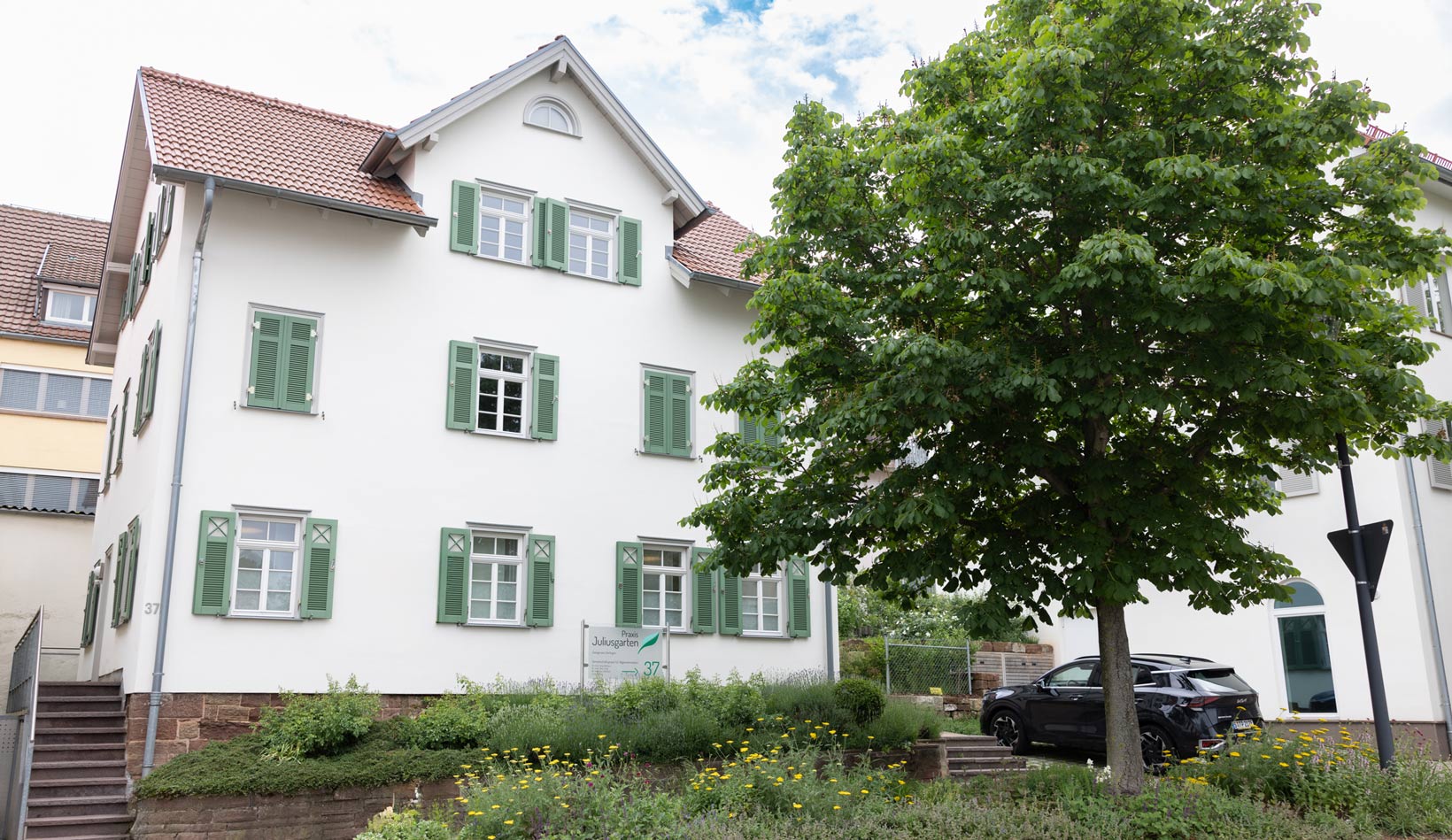 Gebäude der Zweigpraxis in Gerlingen. Es ist ein weißes, zweistöckiges Gebäude mit grünen Fensterläden und roten Dachziegeln.
